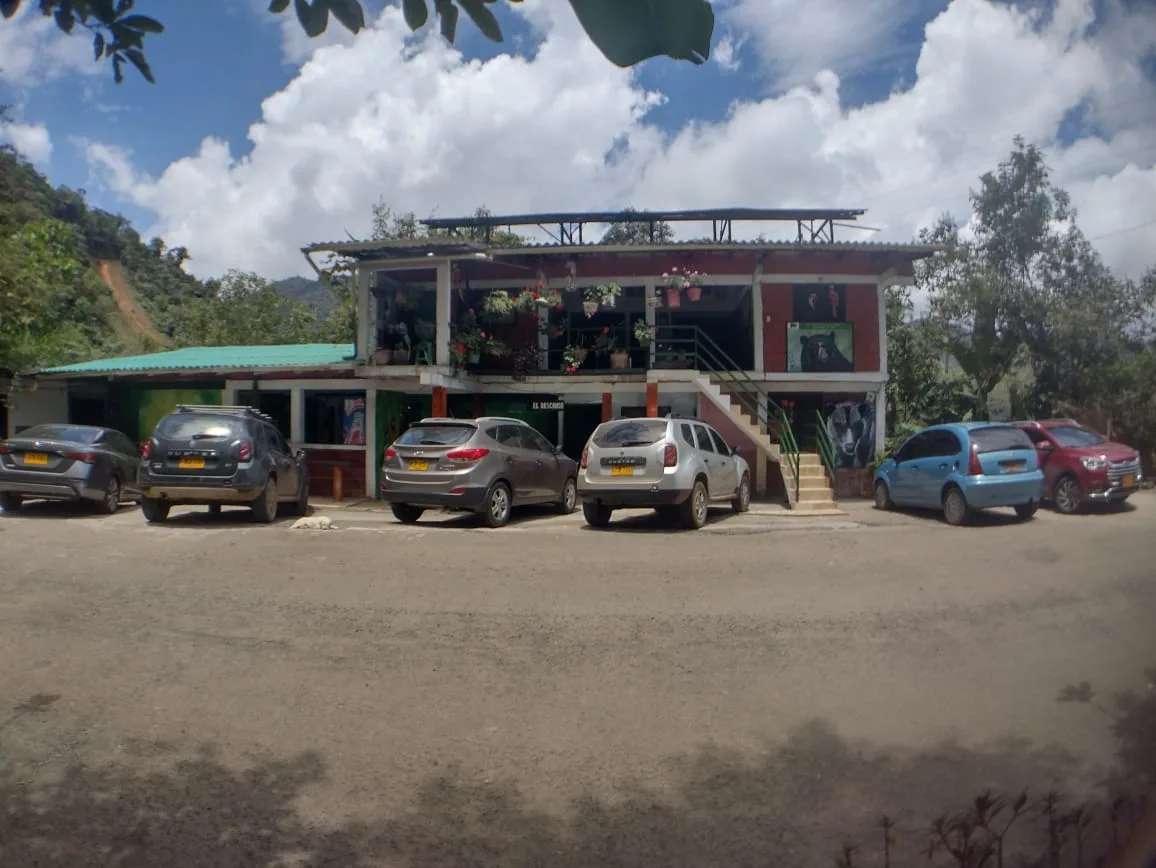 La casa de Doña Dora sobre la antigua vía al mar, con los carros de los visitantes al frente